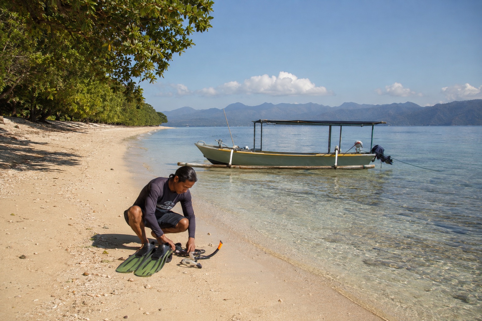 Guide préparant le matériel de snorkeling sur la plage de Gili Layar