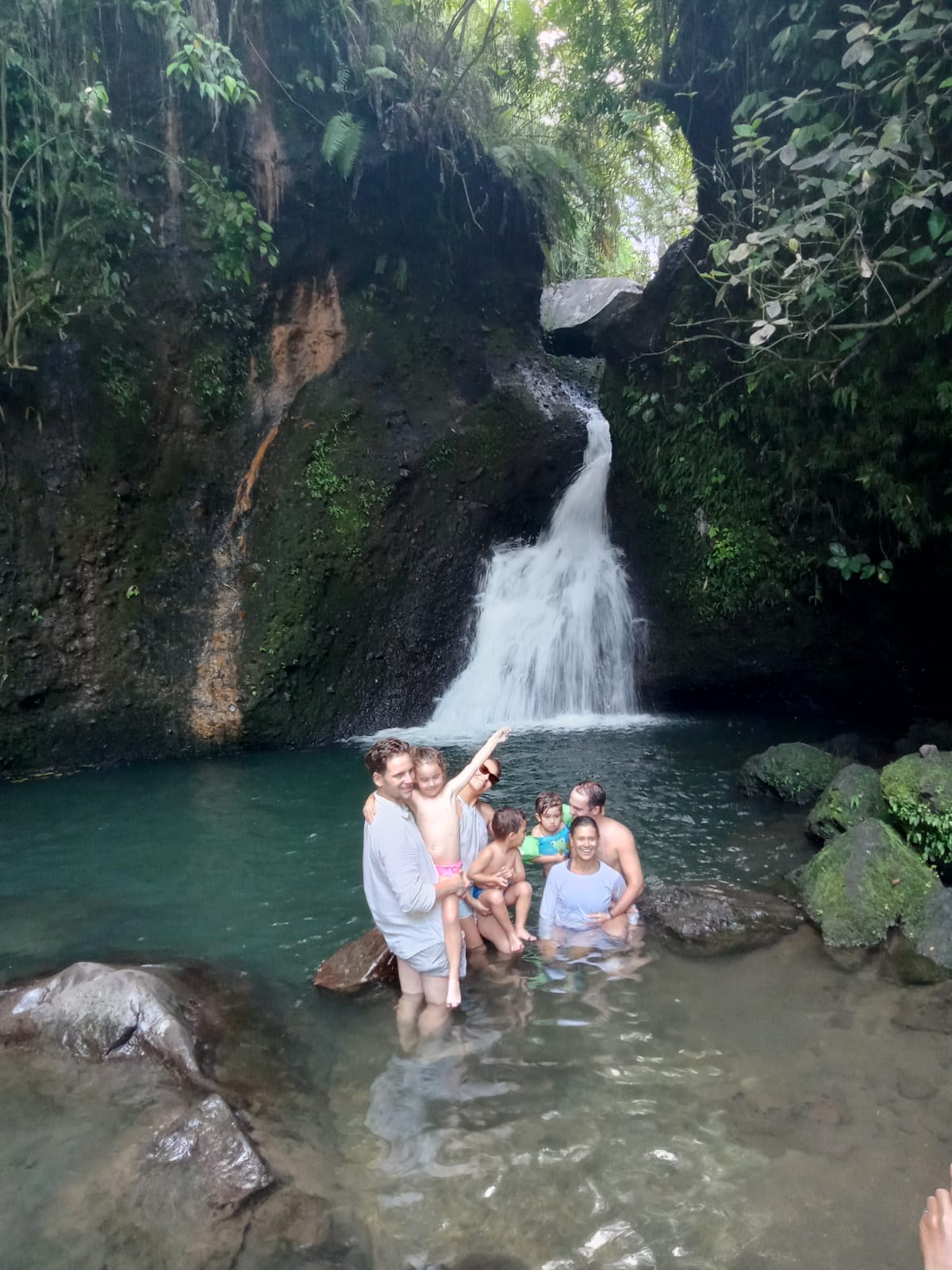 Famille de voyageurs se baignant au pied d’une cascade à Lombok